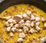 Через 10 минут добавьте курицу с горохом и готовьте до готовности риса.	