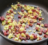 Затем порежьте на небольшие кусочки колбасу (отлично подойдут охотничьи) и добавьте в сковороду. Готовьте еще около 2 минут.	