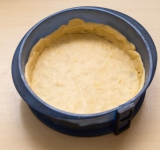 Достаньте тесто из холодильника, разделите на две части (одна побольше). Большую часть раскатайте и выложите на дно формы для пирога, придавите тесто к дну и бокам формы.	