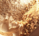 В полученную смесь добавьте орехи и овсяные хлопья. Перемешайте до однородной массы.	