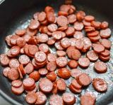 Колбаски порежьте на небольшие кусочки и сковороде в кастрюле на сливочном масле. Снимите с плиты.	