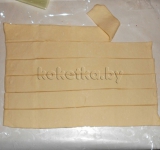 Размораживаем пласт слоеного дрожжевого теста, раскладываем на рабочую поверхность и нарезаем на длинные полоски. Их количество должно быть по числу сосисок.	