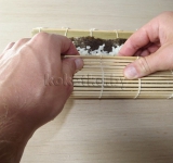 С помощью бамбуковой салфетки сворачиваем роллы.