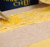 Сверху кладем еще одну полосу теста и выкладываем цедру. Повторяем и с остальными полосками.