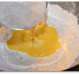 В большую миску просеиваем муку, соль и сахар. Делаем углубления и выливаем туда яйца. Туда же выливаем поднявшуюся опару.