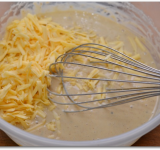 Добавляем растительное масло, дижонскую горчицу. Хорошо перемешиваем тесто. Дижонская горчица считается самой популярной в мире, а её название происходит от французского города Дижон. Если нет горчицы, можно не добавлять, это опционально. Добавляем в массу тертый сыр.	