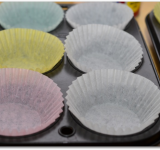 В формы для маффинов вставляем бумажные юбочки и слегка сбрызгиваем их растительным маслом.