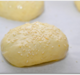 Руками формируем пирожки и выкладываем их на противень, засланный пергаментной, бумагой швом вниз. Даем постоять 20 минут, затем смазываем пирожки смесью из яйца и сливок и по желанию посыпаем кунжутом.