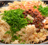 Добавляем на сковороду рис, изюм, мякоть помидора, мяту и 3 ст. ложки петрушки. Все хорошо перемешиваем и снимаем с огня.