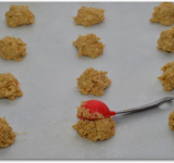 Противень застилаем пекарской бумагой и слегка смазываем маслом. При помощи столовой ложкой выкладываем тесто на расстоянии около 6 см друг от друга.	