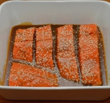 Когда пройдет время, разогрейте духовку до 170 градусов. Достаньте форму с рыбой из холодильника, посыпьте рыбу кунжутом и отправьте в духовку.