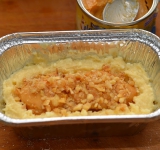 В смазанную маслом формочку на дно выкладываем слой теста, затем кладем 2 чайных ложки вареной сгущенки и посыпаем орешками.