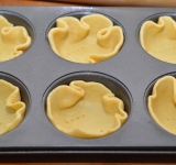 Достаем тесто, тонко раскатываем, нарезаем кружки на пару см больше диаметра формочек. Формочки смазываем маслом, выкладываем туда тесто. Дно формочек накалываем вилкой и ставим в предварительно разогретую духовку на 10 минут, чтобы подсушится.