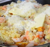 Когда рис приготовился, добавляем сыр и 2 ст. ложки сливочного масла, накрываем крышкой и даем настояться пять минут.