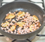 Ветчину измельчаем небольшими кубиками и добавляем их к грибам, слегка обжариваем. Убавляем огонь до минимума.