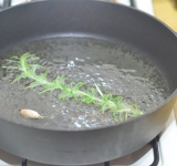 В глубокую сковороду наливаем растительное масло слоем в 3-4 см. Разогреваем масло на среднем огне, добавляем туда веточку розмарина и неочищенный зубчик чеснока, через минуту чеснок и розмарин вынимаем и выкидываем.