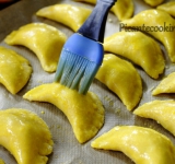 Пирожки выкладываем на противень, застеленный пергаментной бумагой, смазываем тесто взбитым яйцом с водой и ставим противень в разогретую духовку.