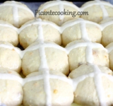 Когда булочки подросли, смазываем тесто взбитым яйцом. Перемешиваем муку с 4-5 ст. ложками воды до однородности. Полученной массой наполняем кондитерский мешок и рисуем на каждой булочке крест.