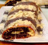 Пока помадка не застыла, щедро поливаем ей поверхность рулета. Посыпаем рулет маком и орехами, придавая желаемый узор. Даем рулету полностью застыть.