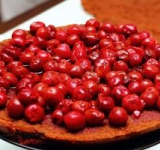 Приступаем к сборке. Смешиваем оставшийся компот и 50 мл кирша. При помощи овощерезки делаем шоколадную стружку. Первый корж пропитываем третью жидкости для пропитки, сверху выкладываем половину вишен с сиропом.