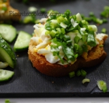 Для начала отварите яйца в крутую, остудите. Огурец нарежьте тоненькими кружочками. Кусочки батона нарежьте на порции и обсушите на сухой сковородке или в тостере. Порубите остуженные яйца на мелкие кубички. Нарежьте зеленый лук.