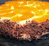 Поверх торта красиво выкладываем сегменты апельсина, края посыпаем шоколадной стружкой. Остатками глазури смазываем поверхность фруктов. Ставим торт в холодильник на час.