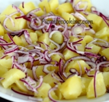 Нарезаем картофель крупными кусочками и выкладываем на большое сервировочное блюдо первым слоем. Сверху равномерно раскладываем измельченный полукольцами лук.