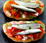 Поверх бутербродов выкладываем пару килек и сбрызгиваем оливковым маслом. Брусккетты готовы. Приятного аппетита!
Cсылка на оригинальный рецепт: www.picantecooking.com/recipe/brusketty-s-pomidorami-i-kilkoi