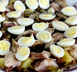 Сверху распределяем каперсы. Перепелиные яйца отвариваем, чистим и каждое разделяем пополам. Выкладываем яйца в один слой на салат.