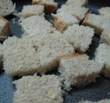 Нарезаем батон крупными кубиками, выкладываем в один слой на противне и подсушиваем в предварительно разогретой духовке 5 минут. Булочки должны быть хрустящими, но мягкими внутри.	