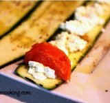 Для начала нарежьте цуккини на тонкие длинные полоски. Лучше всего вооружиться овощечисткой, потому что полоски должны получиться достаточно толстыми, чтобы не рваться при скручивании и достаточно тонкими, чтобы их возможно было свернуть. Возьмите большое блюдо и сбрызните его маслом, а затем посыпьте черным молотым перцем. Выложите полоски цуккини, немного прижмите, чтобы они промакнулись в масло, а затем переверните на другую сторону.