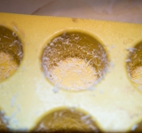 Смажьте форму для суфле маслом, затем посыпьте тертым сыром и распределите по всей поверхности формочек, чтобы сыр распределился по всей поверхности формочек.	