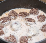 Залейте соус в сковороду к ежикам, накройте крышкой и тушите на слабом огне около 30 минут до готовности.	