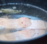 В высокую сковороду или сотейник налейте воду, доведите до кипения и выложите туда рыбу (вода должна прикрывать рыбу). Доведите снова до кипения, убавьте огонь до минимума (чтобы вода слегка только кипела), посолите и поперчите воду и готовьте 12 минут.	