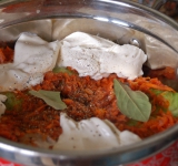 Тем временем приготовим заправку. Натрите морковку на крупной терке, измельчите лук. На разогретой сковородке с маслом обжарьте лук с морковкой до золотистого цвета, затем добавьте томатную пасту, потомите на огне еще минуты 3.
Переложите заправку на голубцы, распределите ее по поверхности. Выложите сметану, специи, лавровый лист.