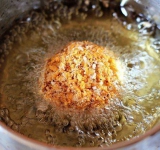 Яйца тщательно взбейте венчиком. Каждый из шариков мороженого аккуратно обваляйте в крошках, затем обмакните в яйцо, а потом снова в крошку. Чтобы шарики не растаяли, перед началом готовки вы можете поместить их в морозильную камеру часа на 3. 
 
Возьмите маленькую кастрюльку с толстым дном и хорошенько разогрейте в ней масло. Каждый из шариков мороженого обжарьте во фритюре секунд 25-30. Каждый шарик выложите на бумагу, чтобы стек весь лишний жир.	