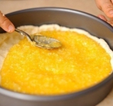 Разогрейте духовку. Первую половину теста равномерно разложите на дне формы, сделав небольшие бортики. Равномерно выложите начинку, размажьте ее по всей поверхности теста. Остальное тесто разомните руками и закройте им лимонную начинку.