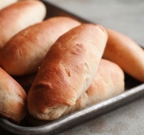 Когда пройдет время, разделите тесто на 3 части, затем каждую часть разделите на 5 продольных рулонов, это и будут наши будущие булочки. В каждой булочке сделайте небольшое углубление в середине. Сверните и выложите на смазанный противень швом вниз. Булочки должны лежать на расстоянии друг от друга. Оставьте булочки постоять на противне минут 30 в теплом месте. 
 
Разогрейте духовку и смажьте каждую булочку сывороткой. Поставьте в духовку и запекайте минут 20-25. Приятного аппетита!	