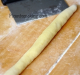 Для начала разогрейте духовку. Запеките картофель, как обычно, до полной готовности, около часа. Когда картошка будет готова, остудите ее, разрежьте на половинки и выскребите мякоть, пропустите ее через пресс для картошки. Выложите мякоть в глубокую миску, соорудив горку. В середине сделайте углубление и выложите в него желтки. Туда же добавьте 1/3 часть муки и соль. Сверху аккуратно распределите еще 1/3 муки. Теперь тщательно замесите тесто. При необходимости можно добавить еще муки. Тесто должно быть однородным, но немножко липким.