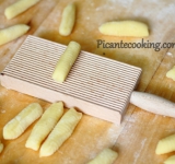 Теперь делаем сами ньйокки. Отделите часть теста и скатайте длинную колбаску. Нарежьте ее на небольшие кусочки, шириной примерно 0,8-1 см. Создайте на каждой палочке рельеф при помощи ножа или специальной доски.Теперь в большой кастрюле вскипятите подсоленную воду и аккуратно опустите в нее ньйокки. Варите минуты 2 после того, как они всплывут. Готовые ньйокки откиньте в дуршлаг и дайте стечь воде, а затем быстро смажьте их сливочным маслом.