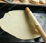 Разделите тесто на 4 части. Каждую из частей разрежьте еще на 5 равных кусочков. Каждый кусочек тщательно обваляйте в муку и раскатайте в тоненький блинчик. Наколите тесто вилкой, затем при помощи скалки перенесите на противень. Выпекайте в разогретой духовке около 4 минут, а затем, воспользовавшись крышкой от кастрюли (или любым круглым предметом) обрежьте края, чтобы получился ровный круг. Делать это нужно немедленно. Проделайте процедуру со всеми кусочками теста. Обрезки от коржей оставляйте, они пригодятся.	