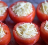 Натрите сыр на крупной терке. Помидоры наполните начинкой, почти до верха, а потом плотно уложите сверху сыр. Слегка посыпьте перцем сверху. 
 
Выложите помидоры на противень и поставьте в духовку минут на 10. Подавайте такие помидоры горячими, украсив свежей зеленью. Приятного аппетита!	