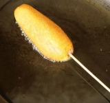 Каждую сосиску опустите в стакан с тестом, а затем, прокручивая, достаньте. Тесто должно полностью обволакивать сосиску.
Обжаривайте сосиски на разогретой сковородке. Если хотите, чтобы сосиска получилась очень красивой, то постоянно крутите ее в масле, тогда кляр ляжет равномерно.
Кляр должен получится золотистым. Не передерживайте его, но и не оставляйте слишком светлым — тесто внутри будет сырым. Как и все блюда на масле — готовые корн доги нужно высушить на бумажных полотенцах.
Подавать эту вкуснятину можно с любыми острыми соусами или просто с кетчупом и горчицей. Приятного аппетита!