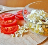 Для начала порежьте баклажан га кусочки, не доходя до края, чтобы получилась гармошка. Положите баклажан в соленую воду на пару часов (это необходимо для того, чтобы с баклажана ушла вся горечь). 
 
Помидоры нарежьте на тоненькие кружочки или полукольца (смотря какого размера баклажан, кружочек помидорки должен помешаться в прорези на баклажане). 
 
Теперь готовим начинку. Вложите брынзу в миску и разомните ее вилкой, а потом добавьте туда нарубленный чеснок и ложку оливкового масла. Добавьте немного сметаны или майонеза и хорошенько все перемешайте так, чтобы получилась однородная масса. Посыпьте базиликлм и снова перемешайте.	