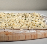 Для начала разморозьте тесто и разогрейте духовку. Сыр натрите на терке.
Противень выстелите пекарской бумагой (мне понадобилось два противня.
В миске взбейте яйцо вместе с перцем, горчицей и водой. Полученной смесью равномерно смажьте лист теста. Затем равномерно посыпьте всю поверхность теста тертым сыром, а потом перемешайте вместе зелень и соль и посыпьте этой смесью сырный слой. Аккуратно прижмите начинку к тесту (не сильно).