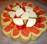 Оставшуюся рыбку нарежьте на кусочки и выложите в серединку. Томаты и перец нарежьте на кружочки и тоже выложите в центр круга. посолите и поперчите начинку, а сверху выложите кусочки моцареллы.
Разогрейте духовку. Пирог оставьте еще минут на 30, для расслойки.
Выпекается такой пирог около 30 минут. Минут через 20 после выпекания, достаньте пирог и смажьте верхушку желтком, тогда корочка будет еще красивее. Приятного аппетита!