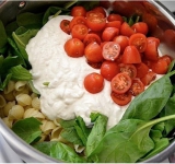 Отварите пасту по инструкции на упаковке. Когда вода в кастрюле вспенится, наберите стакан и отставьте в сторонку.
Пока варится паста, в большой миске смешайте чеснок, рикотту, перец и соль по вкусу. Добавьте стакан отложенной воды и тщательно все перемешайте до однородности. Получится густой кремообразный соус.
Томаты черри нарежьте на половинки.