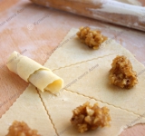 Обратите внимание, что готовое тесто практически не увеличится в объеме и будет пахнуть дрожжами. Так и должно быть. Рабочую поверхность и скалку присыпьте мукой, потому что при всей эластичности это тесто может иногда прилипать. Раскатайте тоненький круг. У круга обрежьте неровные края, а оставшийся круг разрежьте на 8 секторов.  
 
На каждый сектор положите немного начинки и сверните рогалики.	