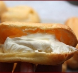 Теперь готовим крем. Для крема тщательно взбейте маскарпоне со сливками и сахарной пудрой до получения пышной кремовой массы. Уберите крем в холодильник, а эклерам дайте полностью остыть.
Теперь начиняем эклеры. Это можно сделать при помощи шприца, а можно поступить проще: надрезать эклеры и положить туда крем ложкой.
Перед подачей охладите эклеры и посыпьте их сахарной пудрой.
Приятного чаепития!