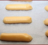 Для начала вскипятите 250 мл воды, потом добавьте к ней масло, соль, хорошенько перемешайте и еще раз доведите до кипения. Снимите с огня и просейте в кастрюлю муку, тщательно перемешайте, должно получиться плотное тесто, однородное, которое будет легко отставать от стенок кастрюли.
В отдельную миску разбейте яйца, хорошо их перемешайте до однородности, а потом, постоянно помешивая, введите тесто по частям. Если вы используете для теста мелкие яйца, то, возможно, понадобится еще одно.
Тесто должно получится мягким и густым, должно хорошо держать форму. Разогрейте духовку. Противень выстелите пергаментом. Переложите тесто в шприц и выкладывайте его в виде колбасок на противень.